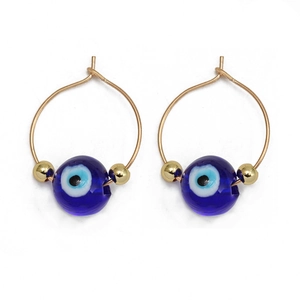 Close-up of gold hoops with blue evil eye beads and golden spacers on white background