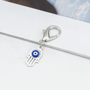 Macro detail of silver Hamsa hand pendant with blue evil eye charm and lobster clasp
