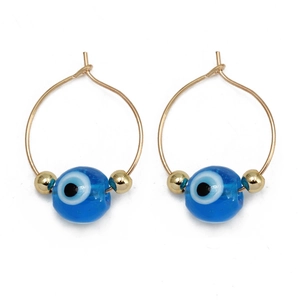 Close-up of gold hoop earrings with blue evil eye beads and small gold spacer details