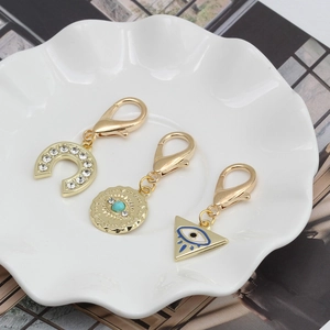 Détail des pendentifs oeil turc dorés avec fer à cheval et fermoirs mousquetons