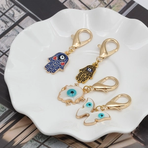 Porte-clés main de Hamsa et mauvais œil dorés avec émail bleu sur un plateau céramique