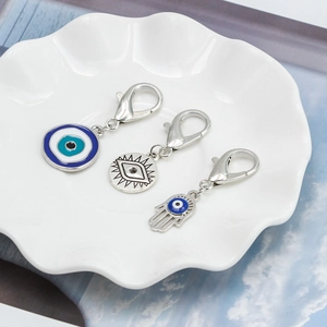Macro detail of three evil eye and hamsa hand charms in a white ceramic dish