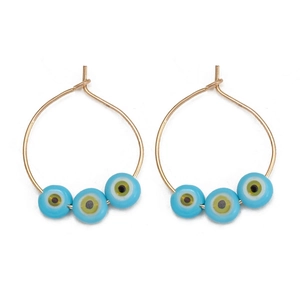Detail of gold hoop earrings featuring three blue evil eye beads on a white background