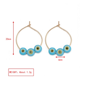 Detail view of 20mm golden hoop earrings featuring 6mm light blue evil eye beads