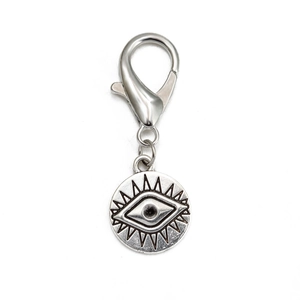 Detail of silver evil eye pendant with lobster clasp and ray-shaped eyelash design