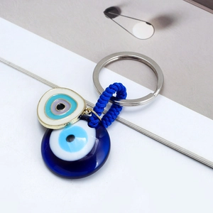 Blue evil eye keychain with two round glass pendants and blue woven rope on minimalist background