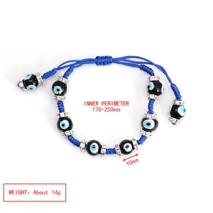 Detailed view of evil eye beads on a blue woven bracelet with metal spacer accents