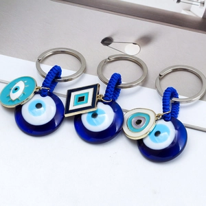 Detailed view of three Evil Eye keychains with blue woven ropes and glass charms