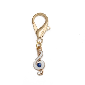 Détail du pendentif clé de sol doré avec émail blanc et cristal bleu étincelant