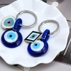 Detail of blue Nazar evil eye keychains with woven cord and round pendant on a plate