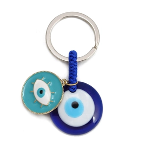 Detail of blue evil eye keychain with enamel lashes and woven rope on white background