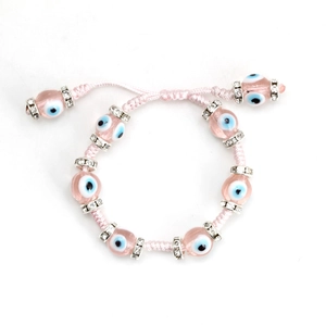 Detailed macro view of pink woven Evil Eye bracelet with sparkling rhinestone spacers