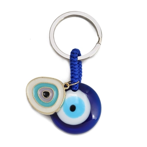 Detailed close-up of blue glass Evil Eye pendant and woven cord on silver keyring
