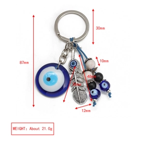 Detail of evil eye keychain with blue glass pendant, silver feather and dimension labels