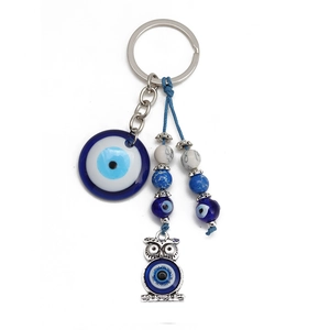 Detailed close-up of blue glass evil eye keychain with silver owl pendant and beads