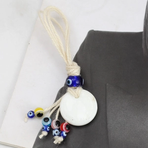 Detail of woven rope Evil Eye ornament with large white pendant and colorful beads