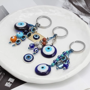 Three assorted Evil Eye keychain pendants in blue resin on a white ceramic plate