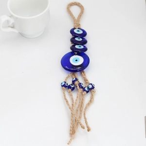 Detailed close-up of blue glass evil eye wall hanging with natural jute tassels