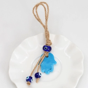 Detail of Hamsa Hand and Evil Eye glass charm with natural jute rope on white background