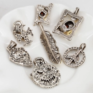 Colgantes punk de plata 925 con calaveras y plumas sobre un elegante plato blanco