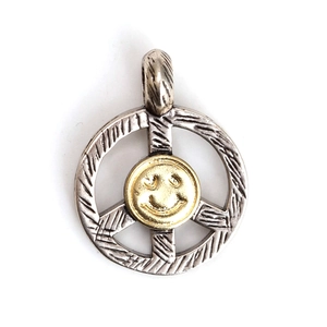 Detalle macro del colgante de signo de paz en plata con carita sonriente dorada y cepillada