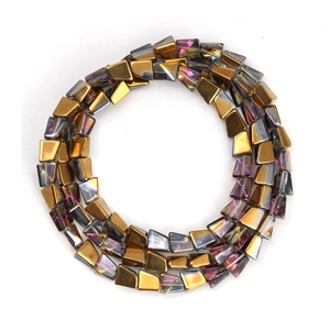 Detailed view of irregular geometric glass beads with metallic gold and iridescent purple coating
