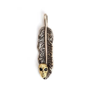 Detalle de colgante de pluma plateada con calavera dorada y grabados de letras artísticas