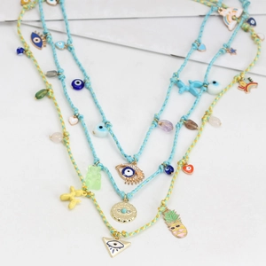 Detail of colorful gummy bear, balloon dog, and evil eye charms on woven necklace cord