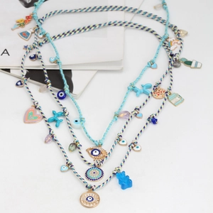 Detail view of multi-layer boho necklace with Evil Eye and blue gummy bear charms