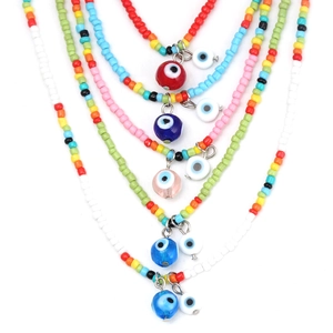 Flat lay of colorful beaded necklaces with evil eye charms on a plain white background