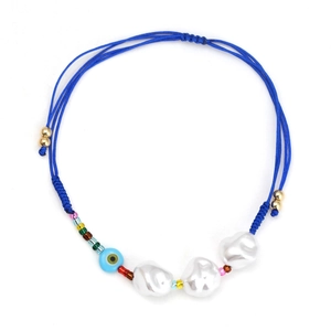 Macro view of adjustable woven blue rope bracelet with baroque pearls and evil eye charm