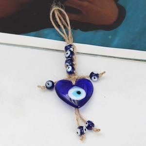 Detail of blue glass evil eye heart pendant with handmade woven hemp rope cord