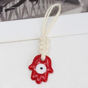 Detailed view of a red Hamsa Hand charm with evil eye and white cotton rope strap