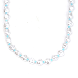 Detail of baroque pearl necklace with blue bead accents on a minimal white backdrop