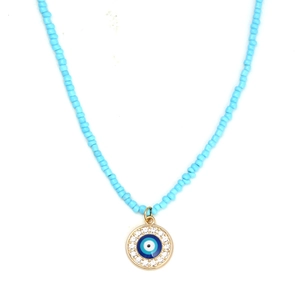 Macro shot of sky blue beads and Evil Eye pendant with clear crystals and gold plating