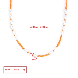 Detail of beaded necklace with orange seed beads and white baroque pearls showing texture