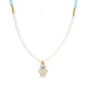 Macro shot of Hamsa Hand pendant with Evil Eye detail on white pearl necklace strand