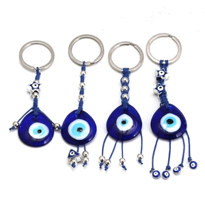 Dettaglio di quattro ciondoli Evil Eye in vetro blu con charms e corde intrecciate