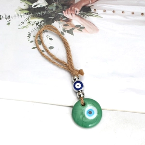 Detailed close-up of a green evil eye pendant with braided rope and decorative beads