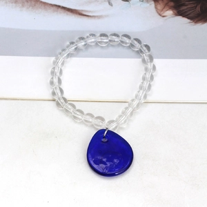 Beaded bracelet with clear round beads and a large irregular dark blue pendant