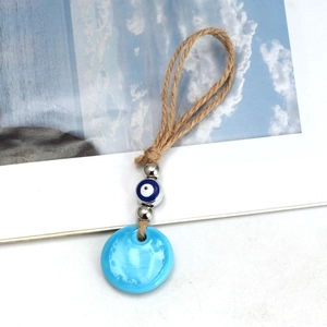Detailed close-up of blue glass Evil Eye pendant with hemp rope and decorative beads
