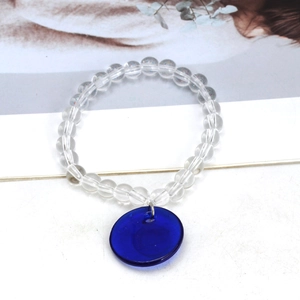 Close-up of beaded keychain with transparent glass beads and a deep blue evil eye charm