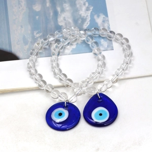 Detailed macro view of two beaded evil eye bracelets with blue teardrop pendants