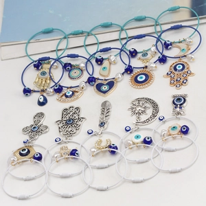 Detail von Evil-Eye-Armbändern mit Hamsa-Hand, Mond und Perlenakzenten in Blau