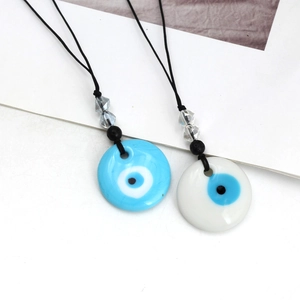 Detailweergave van blauwe en witte Evil Eye glazen hangers met zwart koord en kralen