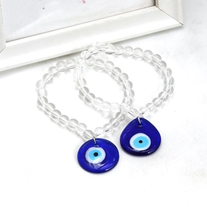 Detail view of two clear glass beaded bracelets with blue evil eye protective charms