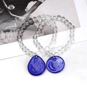 Blue glass evil eye beaded bracelet set with teardrop pendants on white surface