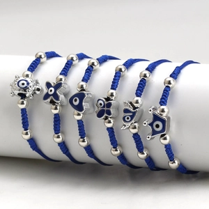 Detail of blue woven rope bracelets with silver evil eye charms and crown heart symbols