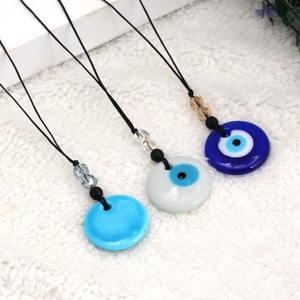 Drie Evil Eye kettingen met gekleurde kralen op een witte pluche achtergrond, diagonaal