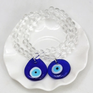 Detailed macro view of two evil eye beaded charms with blue teardrop pendants